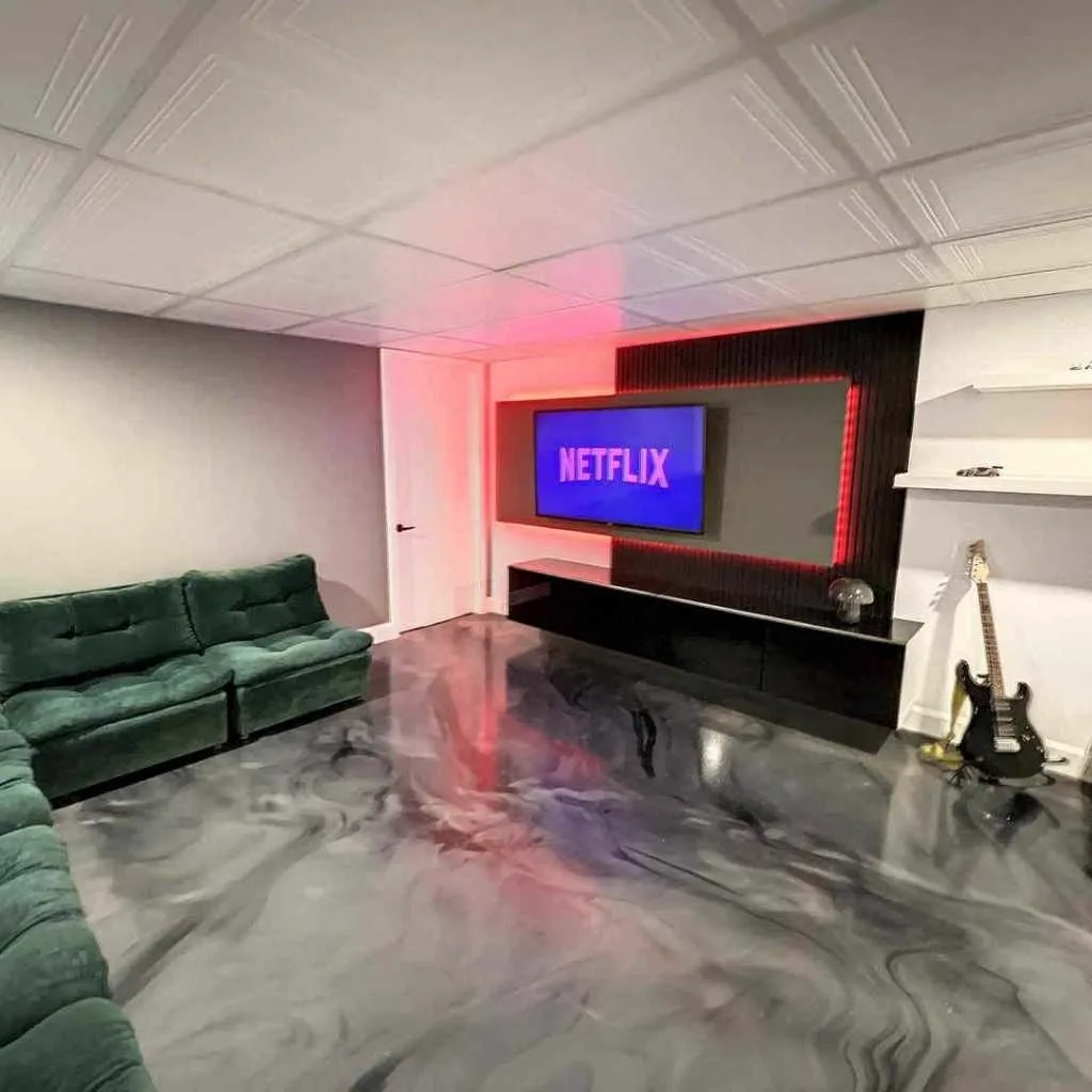 Salle familiale au sous-sol avec plancher d'époxy métallique noir et gris, effet marbré